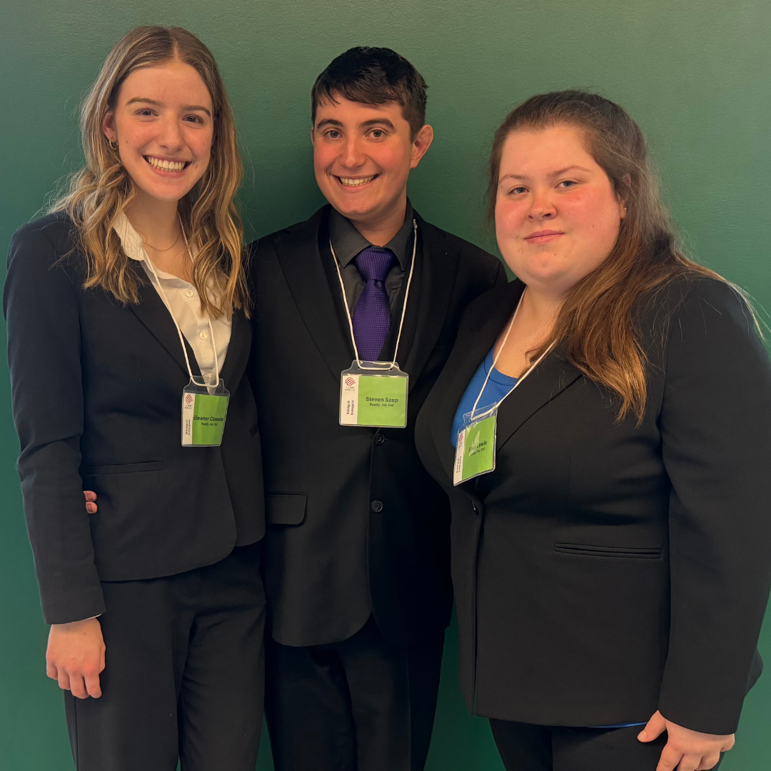 three students smiling after winning an award