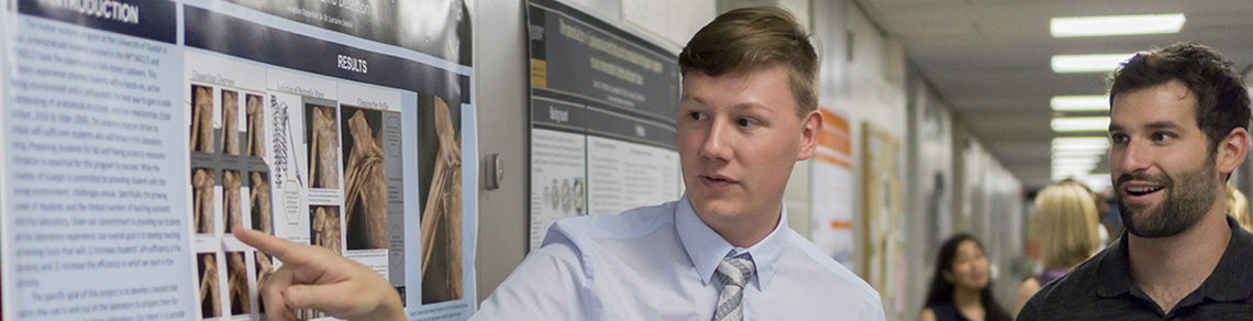 A photograph of a student explaining a photograph of a dissection to another student.