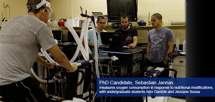 A photograph of a nutritional study. PhD candidate Sebastien Jannas measures oxygen consumption in response to nutritional modifications, with undergraduate students Alex Gamble and Jeovane Sousa.