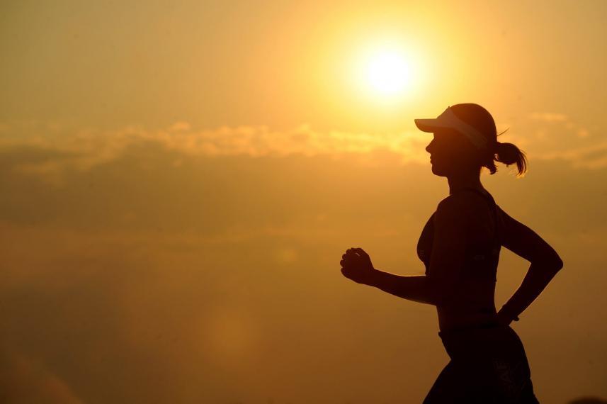 A photograph of a woman running at sunset