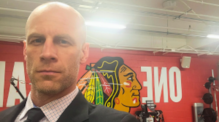 Dr. Jamie Burr, in a suit, taking a selfie in the Blackhawks Gym.