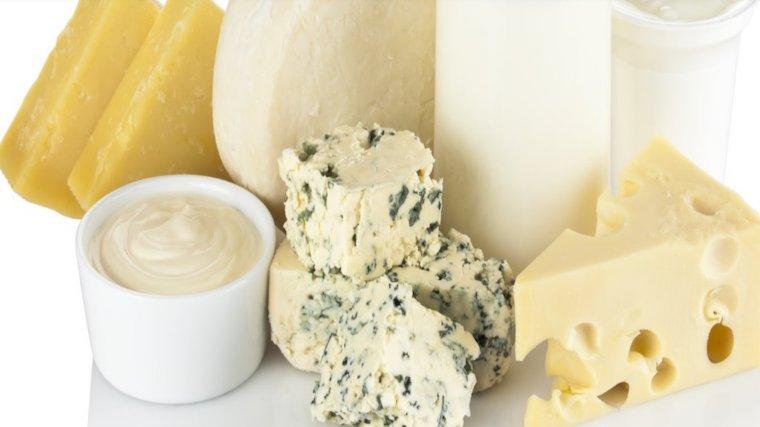 A photograph of various cheeses and a glass of milk.