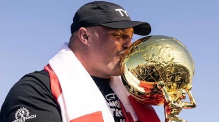 A photo of Mitchell 'Moose' Hopper kissing his Strongest Man Alive trophy