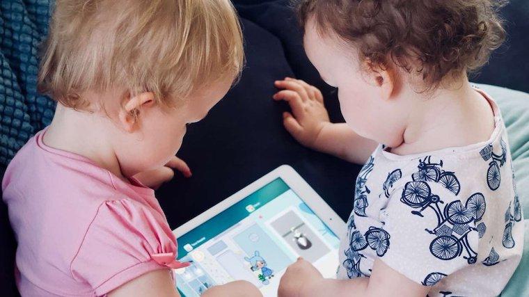 An image of two toddlers using an iPad.
