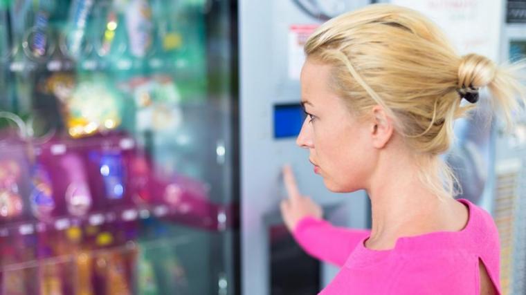 A photograph of a womanchoosing a snack from a vending machine