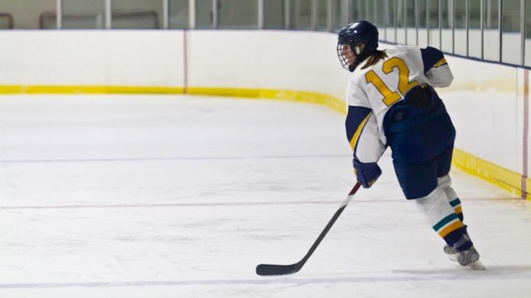 A photograph of a female hockey player on the ice in an icerink.