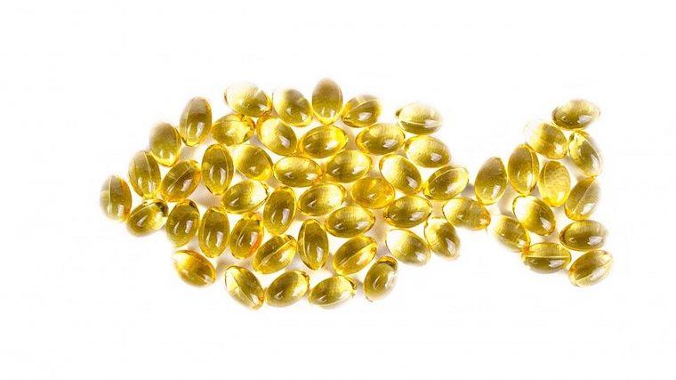 A photograph of Omega-3 capsules arranged in the shape of a fish.