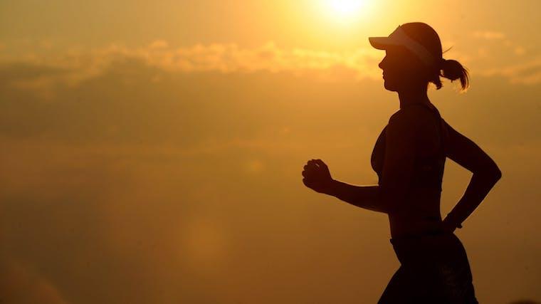 A photograph of a woman jogging at sunset