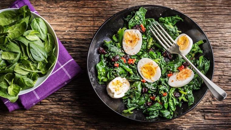 A photograph of a spinach salad with hard-boiled eggs.