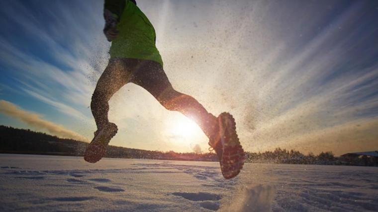 A photograph of a man running on snow