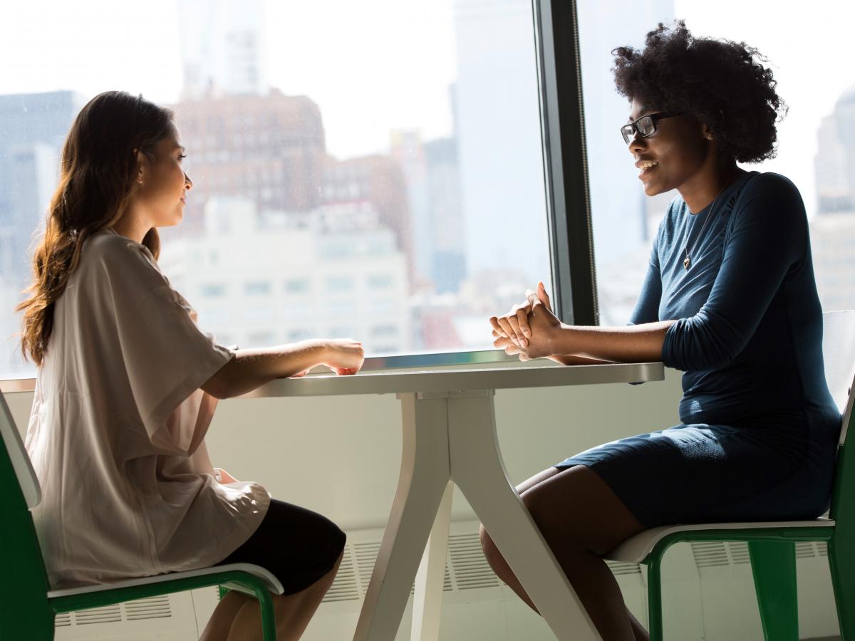 Two women talking across a table. 