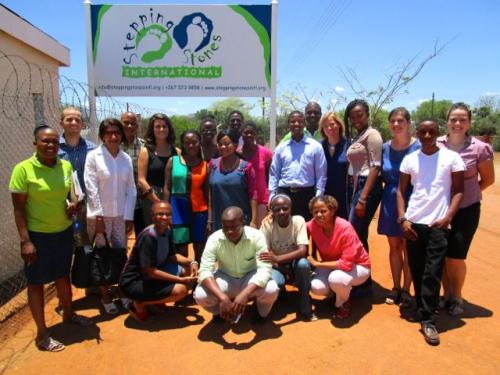 group of people standing in front of a sign and barbed wire fence