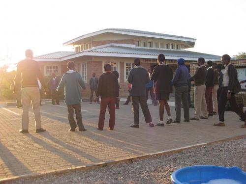 Youth stand in a circle while the sun sets