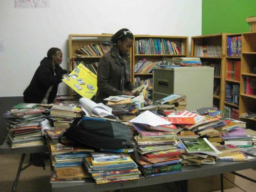 Two women sort stacks of books