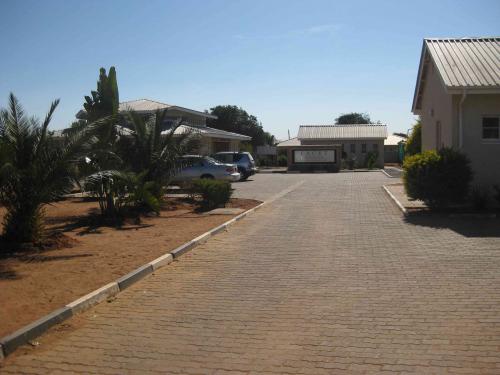 Stone driveway leads towards another white building, blue sky