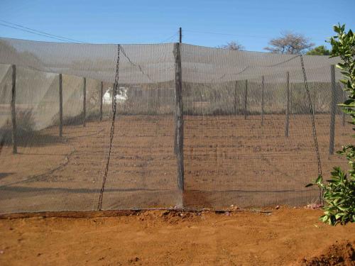 Garden with red dirt surrounded by a screen