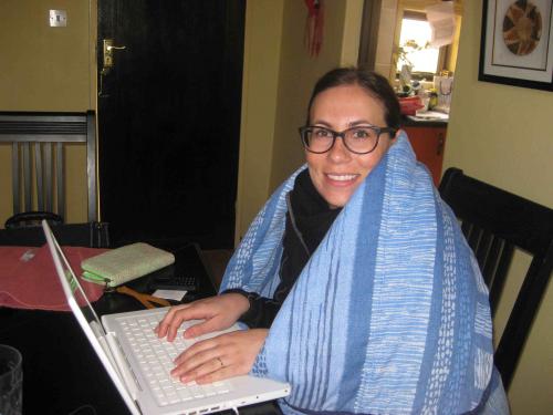 Stephanie sits at a computer covered by a blanket