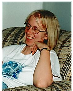 Photo of Leslie Rye. Sitting on a couch and smiling.