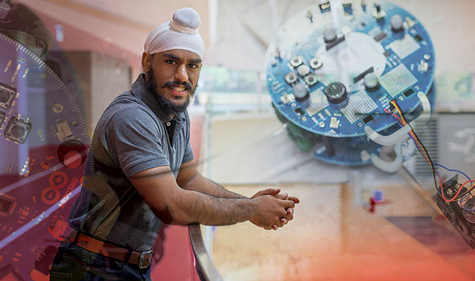 A bearded young male student wearing a white patka and grey polo shirt with jeans, on the balcony of U of G's gymnasium. The image is overlayed with a switchboard related to his engineering studies. 