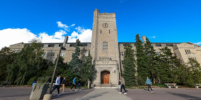 Students in masks walking on campus, Johnston Hall in the background