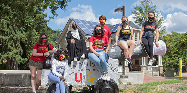 Students in masks sitting on the cannon