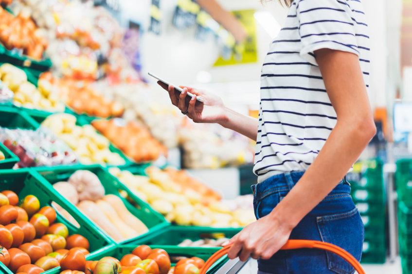 women using phone at grocery store