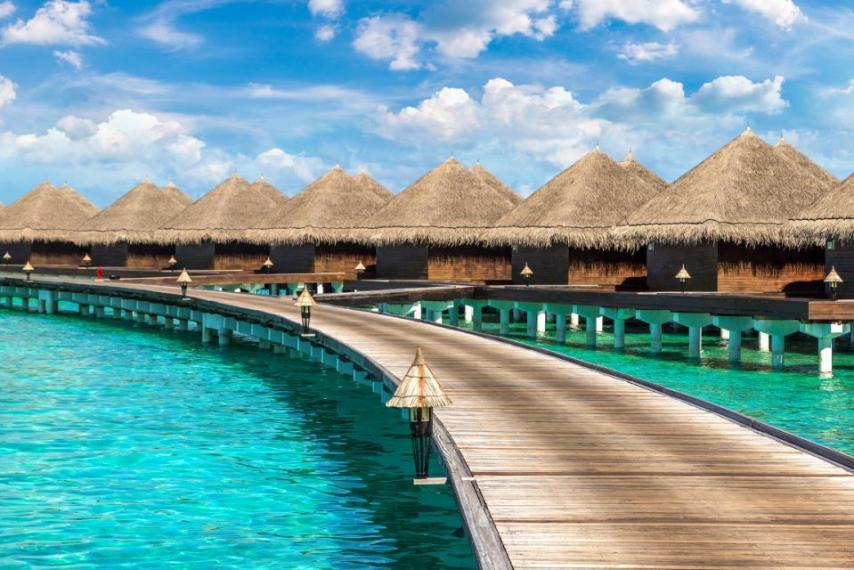 Water Villas (Bungalows) and wooden bridge at Tropical beach in the Maldives at summer day 