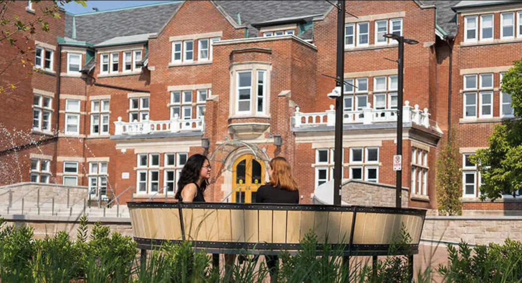 Lang Plaza with two commerce students sitting on a bench.