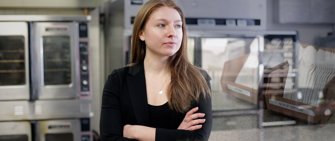 Photo of Emily Robinson standing in a restaurant kitchen, with plastic cutlery layered on top of the image