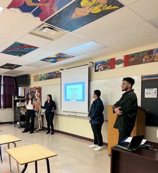 Four Lang students teaching in a high school classroom.
