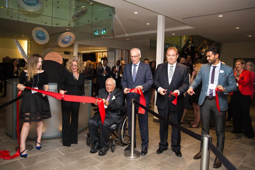 Attendees cut the red ribbon in the foyer of Macdonald Hall.