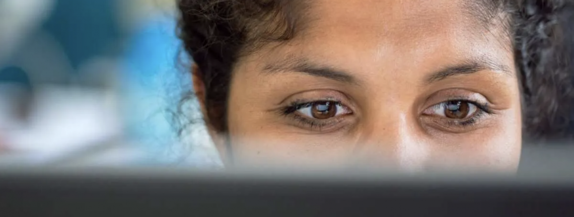 Someone looking at a screen with the back of the screen showing across the bottom of the photo.