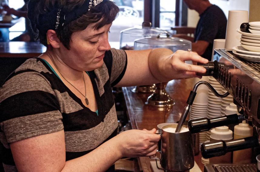 barista foaming coffee in cup