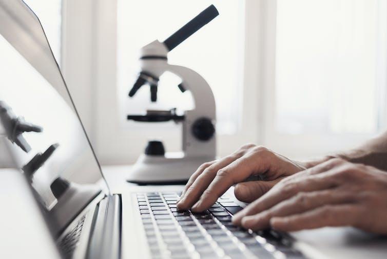 person working at computher with magnifying glass in background