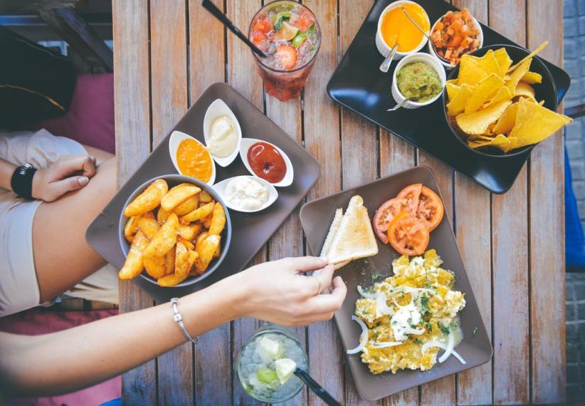 Hands reaching for food on a table, in a restaurant