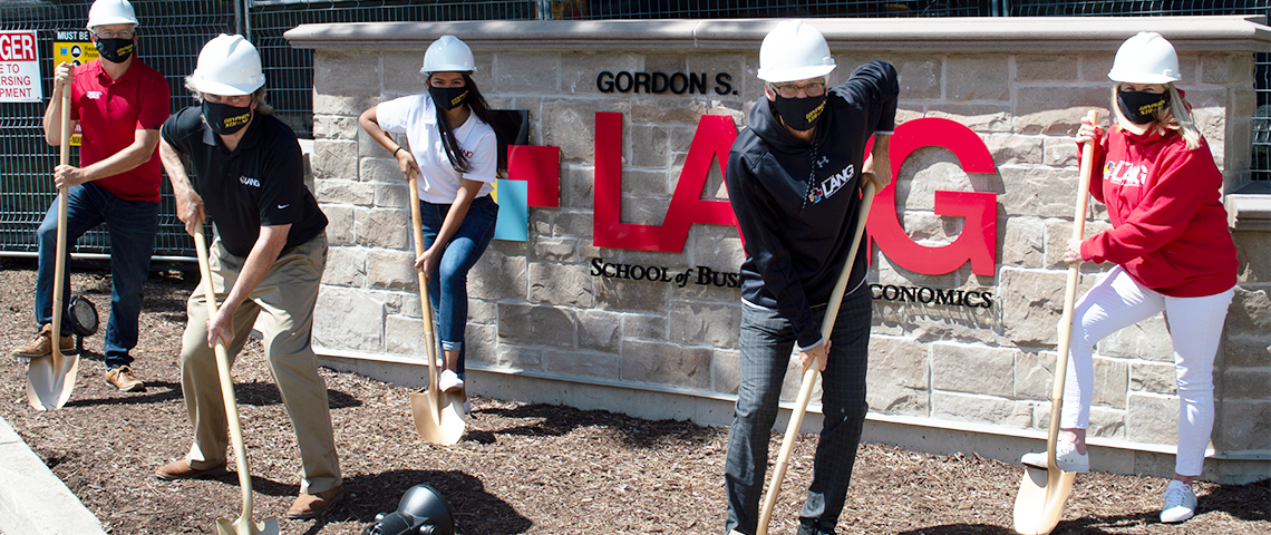 Photo of groundbreaking event, people standing with shovels in the ground