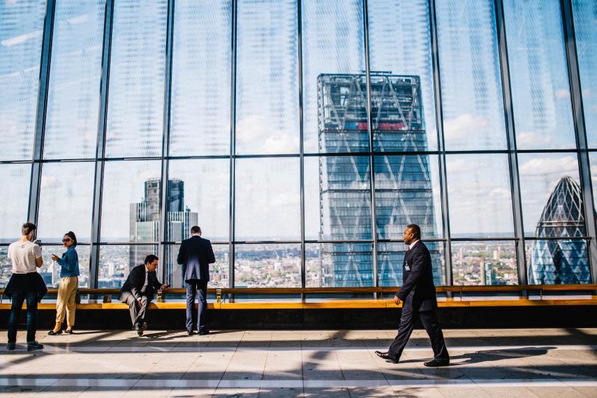 photo of people walking through corporate setting with skyscrapers and city in background