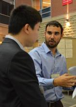 Two attendees discuss research in the Science Atrium