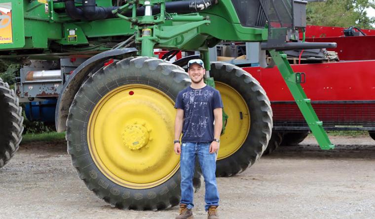 Dylan Sher standing in front of tractor