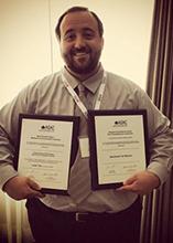 Justin Toth holding awards from the ASAC conference.