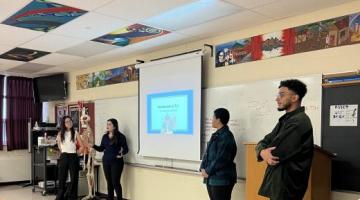 Four Lang students teaching in a high school classroom.
