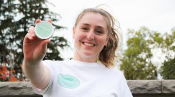 Olivia from Soy Salve holding up their product.