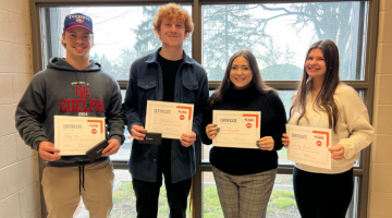 Four commerce students holding their winning certificate