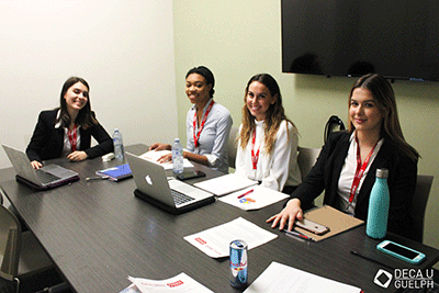 students working in board room on laptops smiling for camera