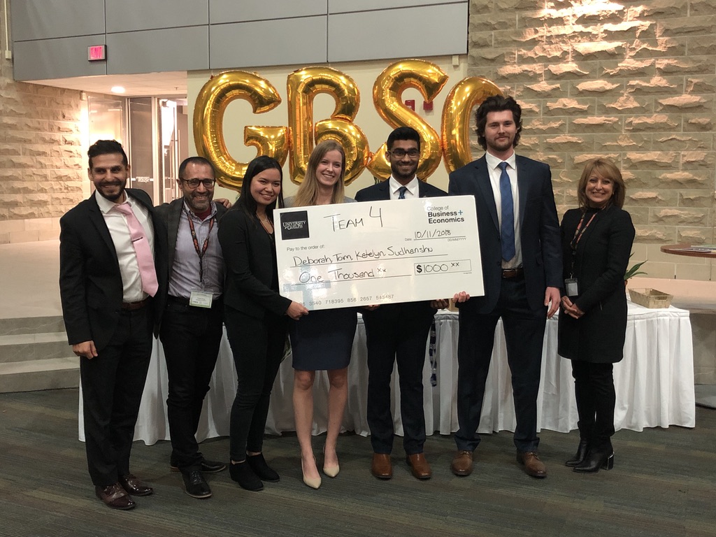 Katelyn Cortina and teammates holding up a cheque after winning a case competition.