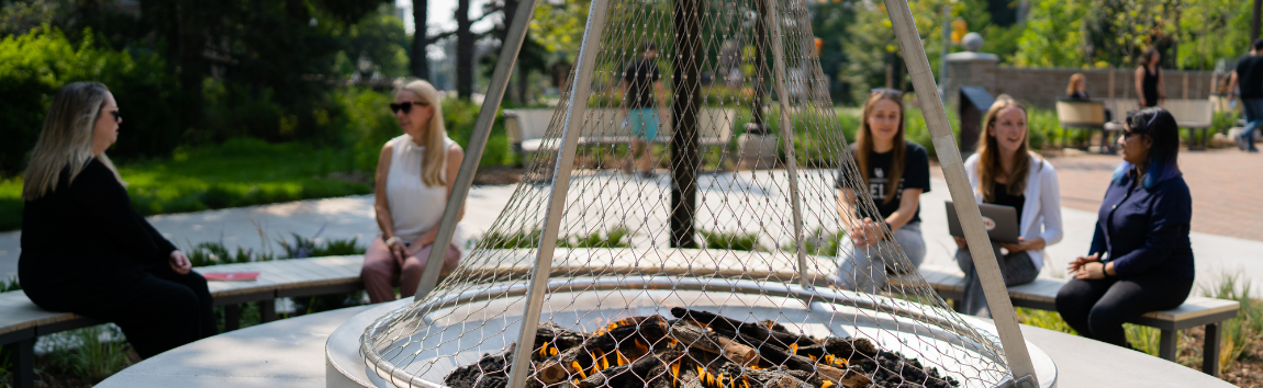 People sitting around the fire pit in Lang plaza.