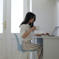 Person working at a desk with a coffee in their hand.