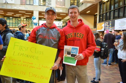 Photo of two male students holding signs for lemonade day in the University Centre