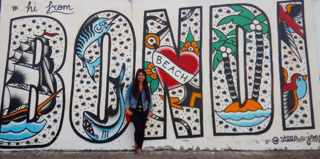 Katie Lo stands in front of the Bondi Beach sign in Australia