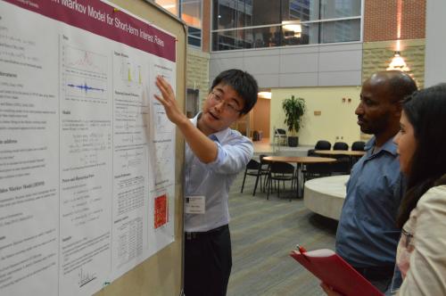 A PhD candidate explains his research to two onlookers at the poster presentation.